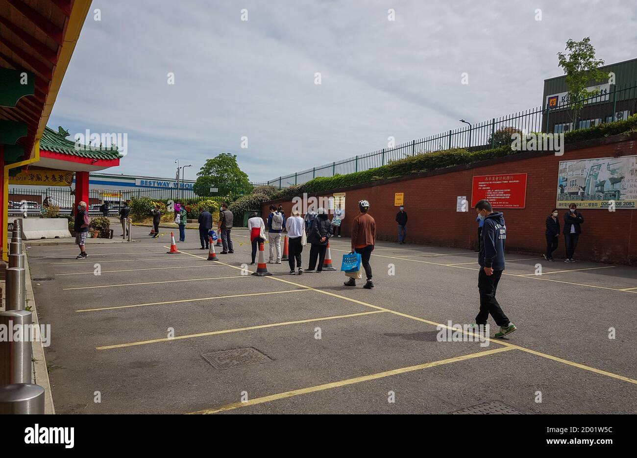 Una lunga coda di persone che osservano le distanze sociali in attesa di fare acquisti in un supermercato. Foto Stock