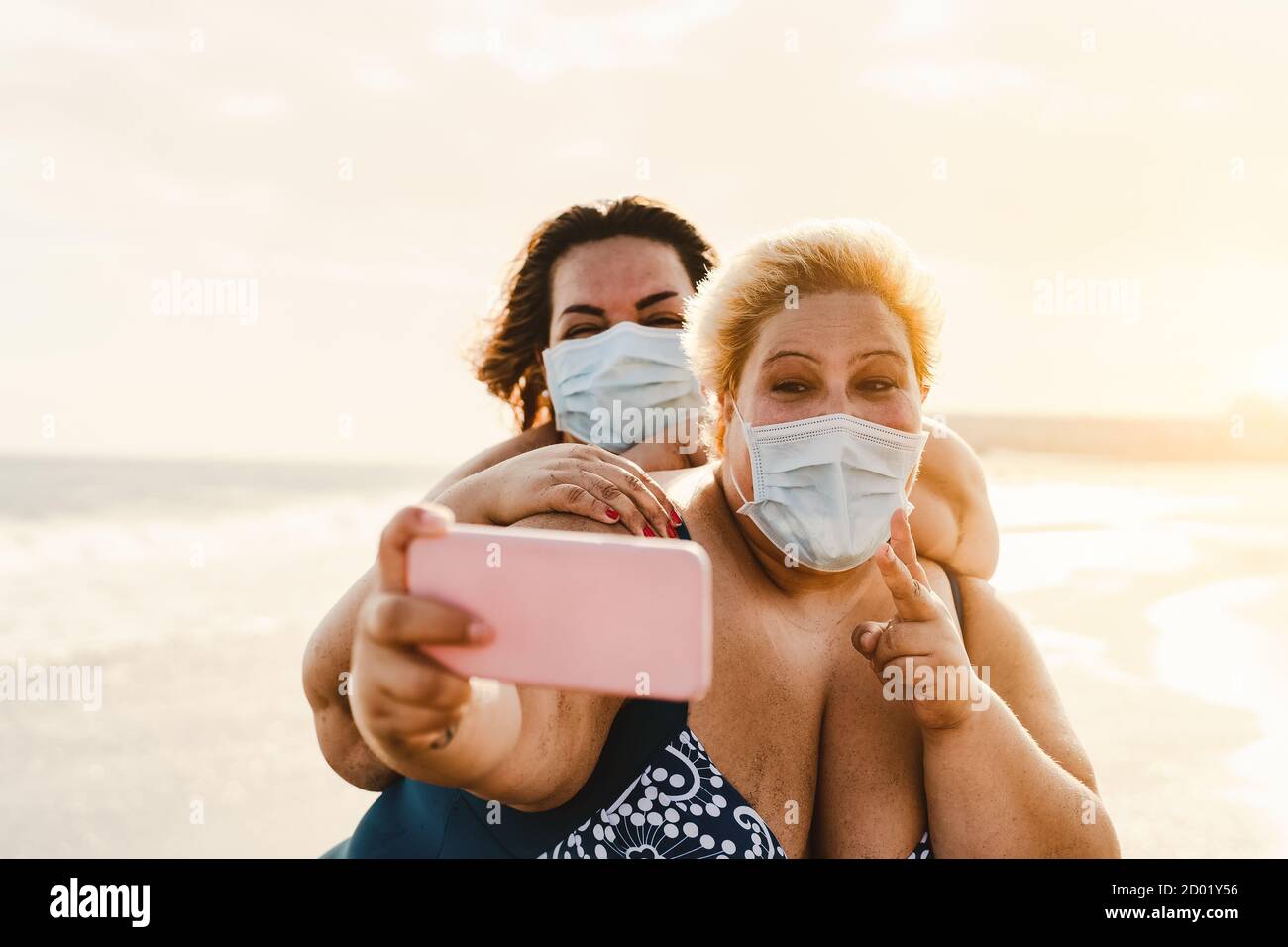 Happy Plus taglia donne che prendono selfie con smartphone mobile su La spiaggia - amici in sovrappeso che si divertono in vacanza durante pandemia del virus corona Foto Stock