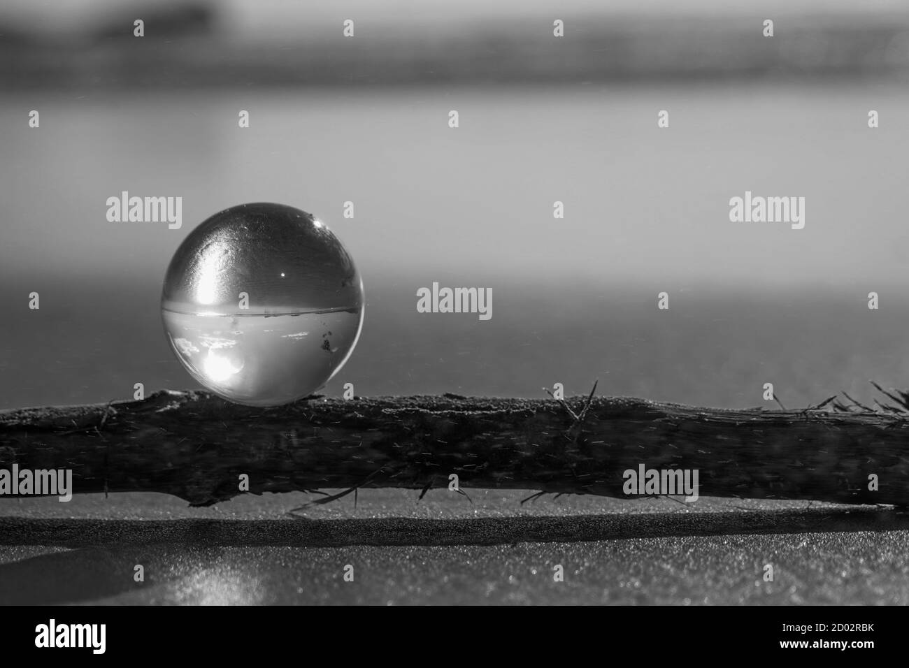Fotografia Cristallo Photo Ball che mostra il riflesso capovolto di cielo spiaggia e onde equilibrate su rocce su spiaggia di sabbia. Foto Stock