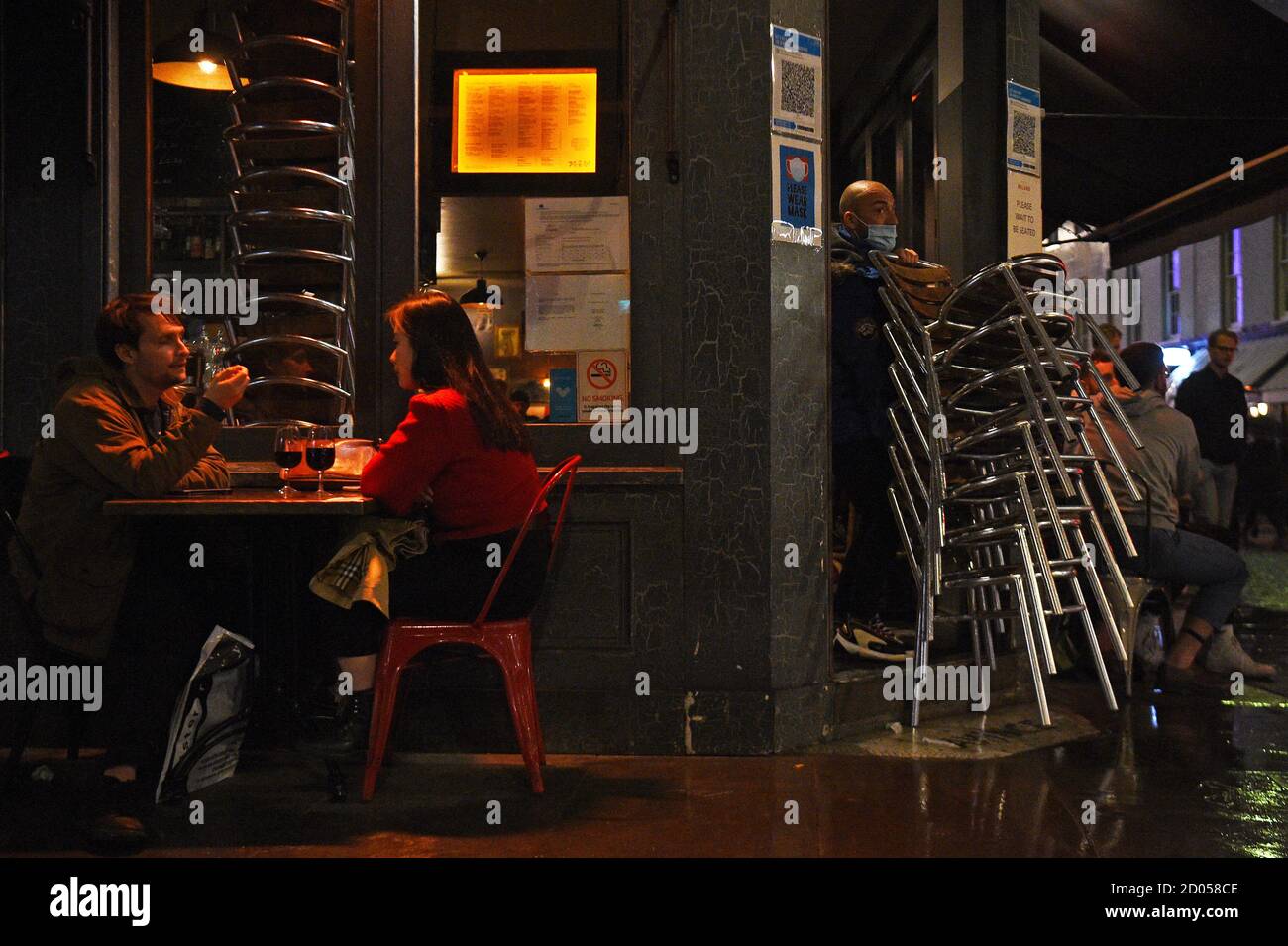 Un operaio tette via sedie fuori un bar a Soho, Londra, davanti alle 22:00 i pub e i ristoranti del coprifuoco sono soggetti a per combattere l'aumento dei casi di coronavirus in Inghilterra. Foto Stock
