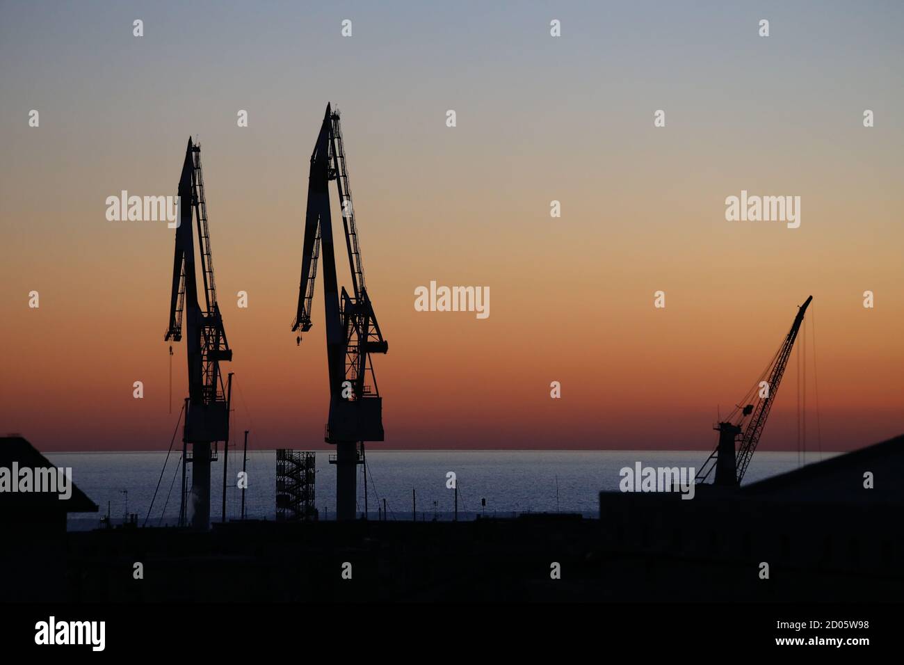 Genova, Italia. Silhouette cantieri navali gru a Genova Sestri Ponente al tramonto contro i suggestivi colori del cielo e del mare Foto Stock