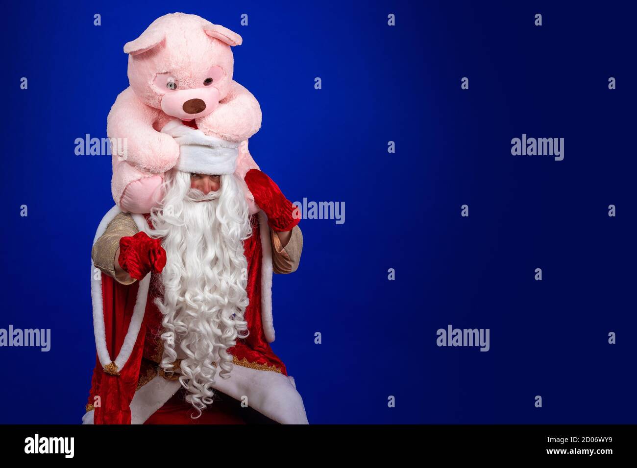 Babbo Natale emozionale con una lunga barba bianca in un cappotto rosso e cappello bianco in posa con un grande orsetto rosa. Foto Stock