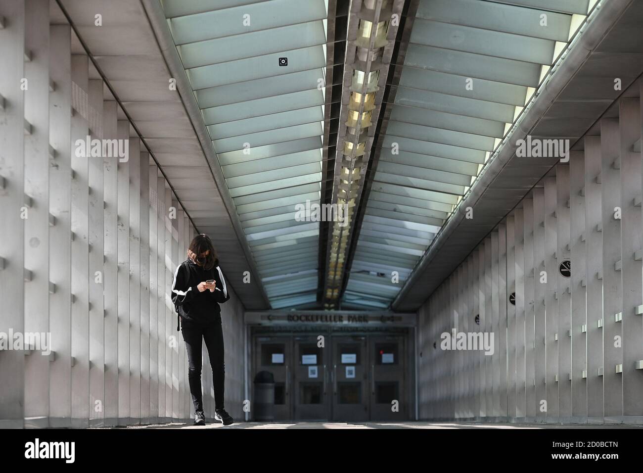 New York City, Stati Uniti. 02 ottobre 2020. Una studentessa della scuola superiore Stuyvesant guarda il suo smartphone mentre attraversa il ponte Tribeca, New York, NY, 2 ottobre 2020. New York City Public High Schools ha riaperto per l'insegnamento di persona il 1 ottobre, la terza e ultima fase per la riapertura di tutte le scuole, dalla Pre-k alle High Schools con l'uso obbligatorio di maschere, una migliore ventilazione e controllo della temperatura. (Anthony Behar/Sipa USA) Credit: Sipa USA/Alamy Live News Foto Stock