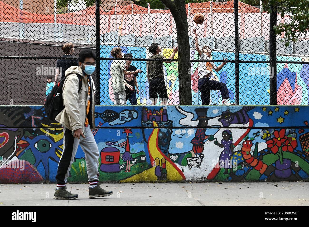 New York City, Stati Uniti. 02 ottobre 2020. Uno studente della Stuyvesant High School cammina oltre il muro dipinto di un parco giochi della scuola lungo Chambers Street, New York, NY, 2 ottobre 2020. New York City Public High Schools ha riaperto per l'insegnamento di persona il 1 ottobre, la terza e ultima fase per la riapertura di tutte le scuole, dalla Pre-k alle High Schools con l'uso obbligatorio di maschere, una migliore ventilazione e controllo della temperatura. (Anthony Behar/Sipa USA) Credit: Sipa USA/Alamy Live News Foto Stock