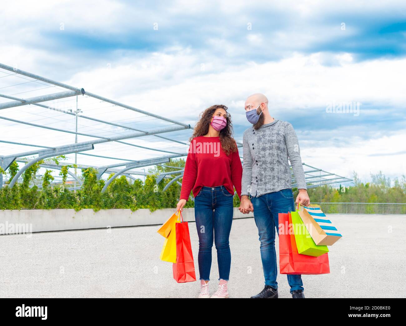 coppia di un uomo e una donna che indossa maschera di faccia tenendo le mani dopo lo shopping sulle vendite per il venerdì nero. concetto circa consumismo e divertimento per acquistare Foto Stock