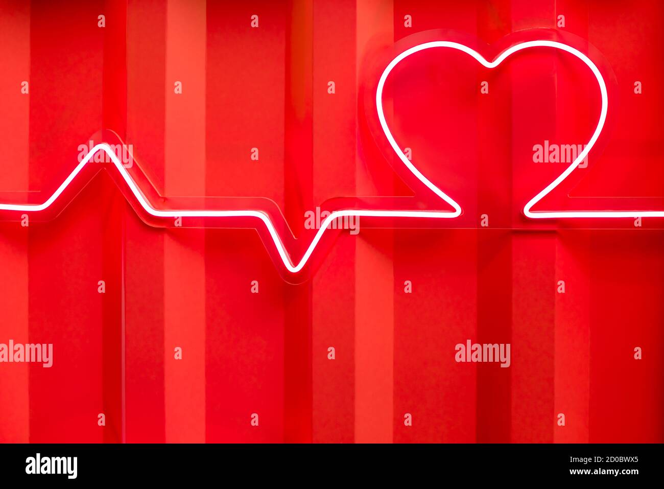 Forma del cuore al neon rosso e linea del battito cardiaco sulla parete metallica vista ravvicinata Foto Stock