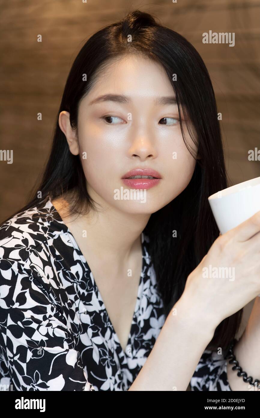 Donna americana cinese che tiene una tazza di caffè in un caffetteria con area fotocopie Foto Stock