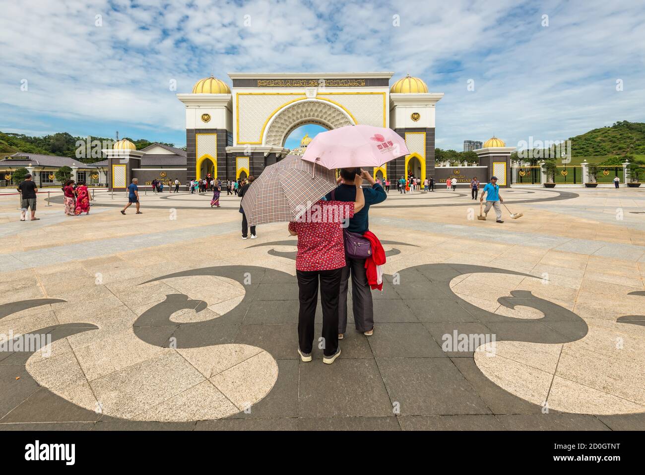 Kuala Lumpur, Malesia - 2 dicembre 2019: Coppia di turisti sotto l'ombrello in piedi di fronte alla porta del Palazzo reale Istana Negara (Istana N Foto Stock