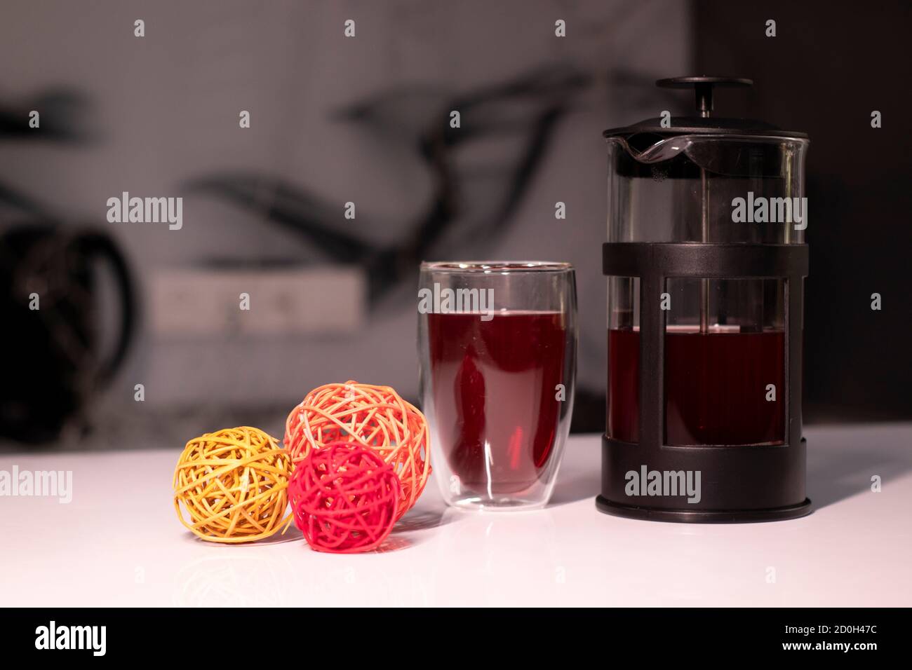 Stampa francese e tè in vetro a doppio fondo accanto alle palle intrecciate per l'arredamento. Foto Stock