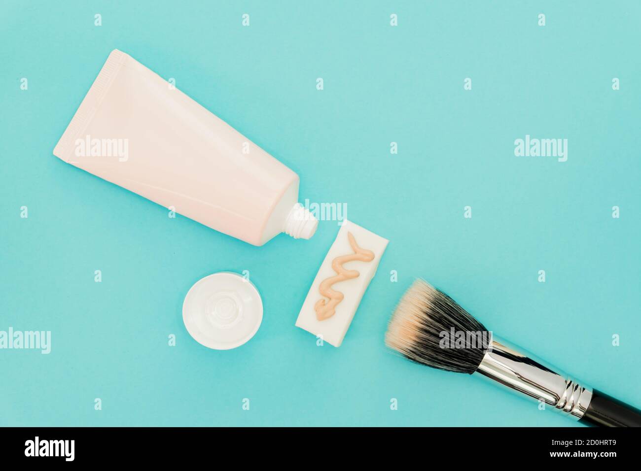 Liquido fondazioni fluido in tubo su spugna trucco e pennello trucco su sfondo blu. Foto Stock