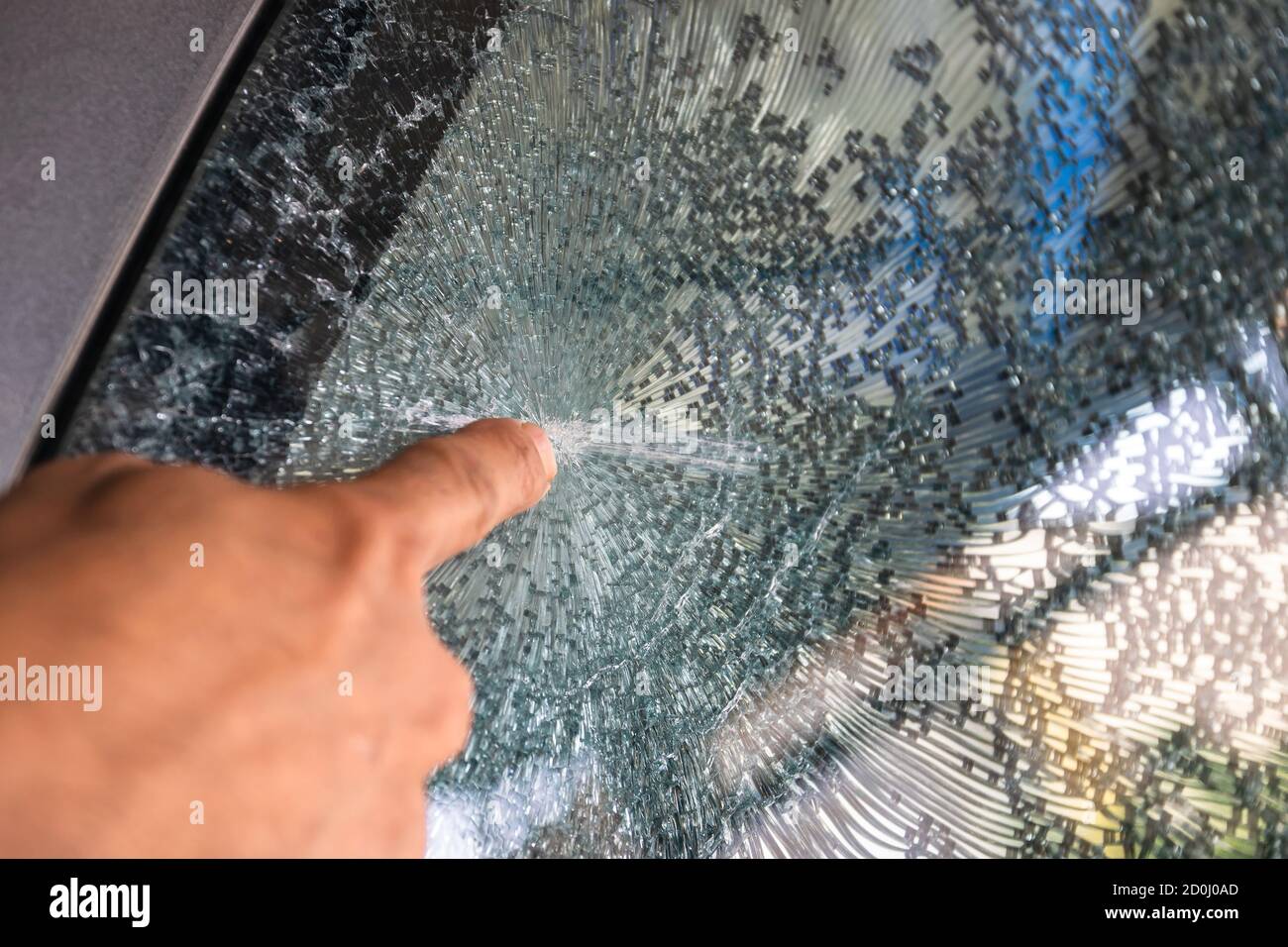 La mano dell'uomo ha puntato sulla spaccatura del parabrezza causata da un incidente sulla strada. Foto Stock