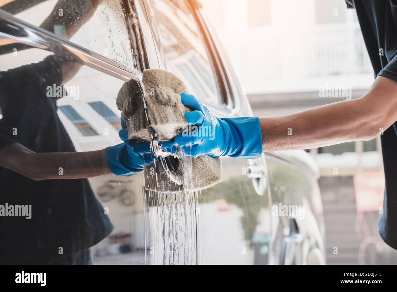 Personale addetto al lavaggio auto che indossa guanti di gomma blu  utilizzando una spugna inumidita con acqua e sapone per pulire l'auto Foto  stock - Alamy