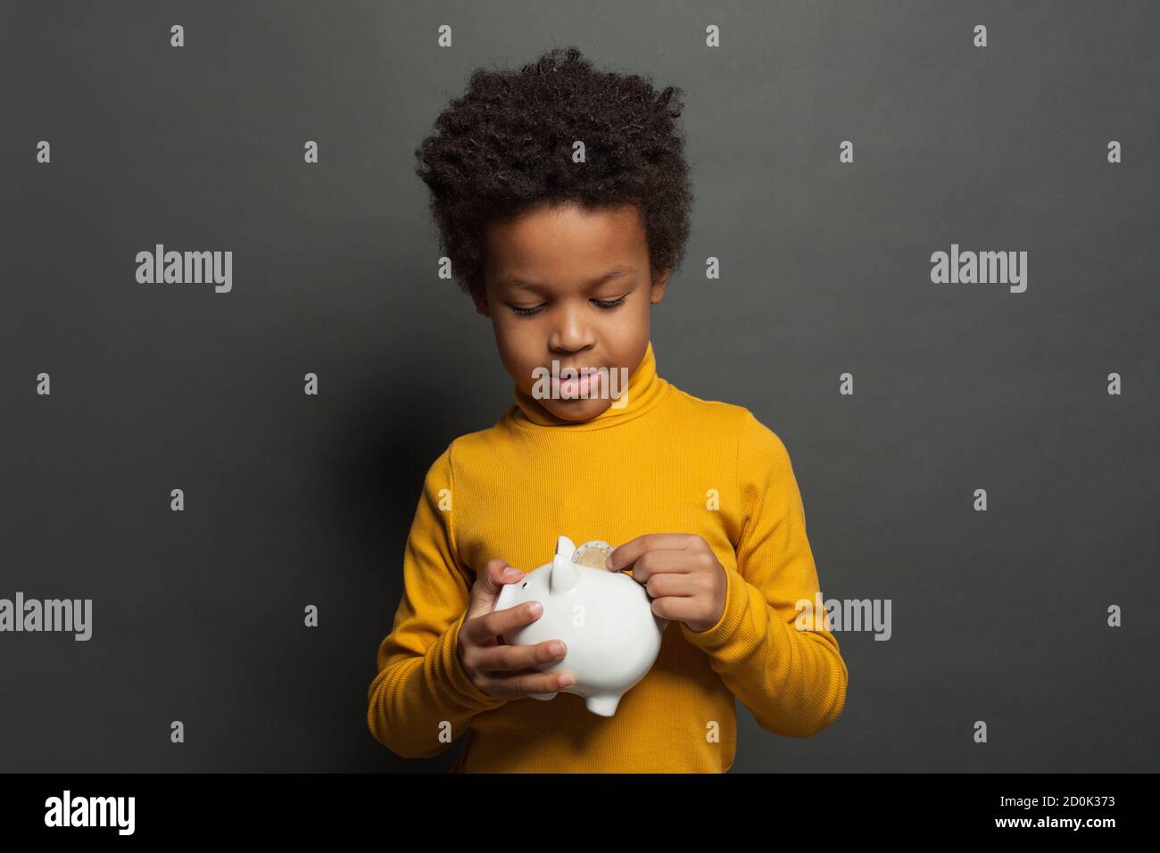 Bambino nero che mette in moneta di banca di soldi Foto Stock