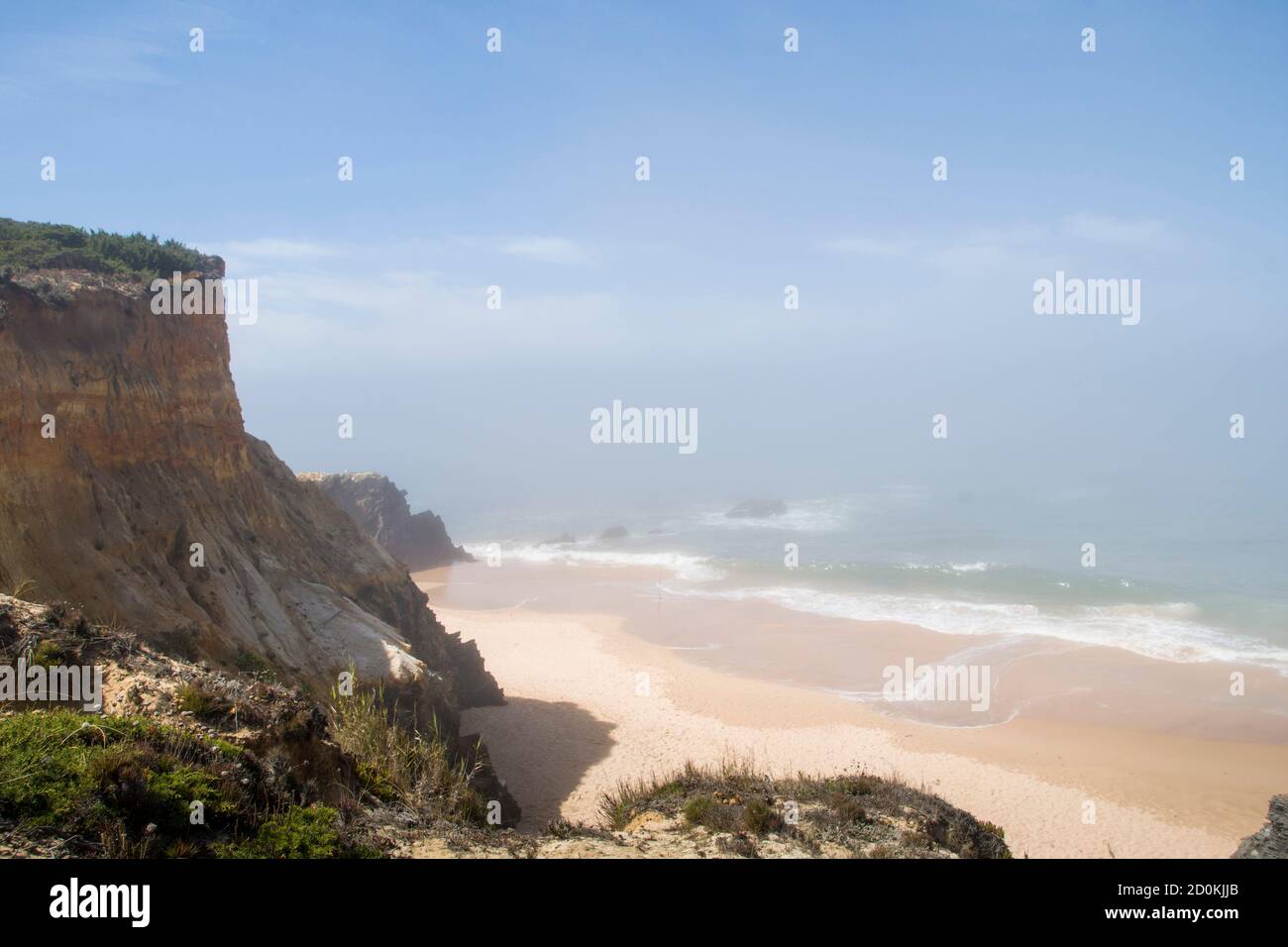 La spiaggia dell'europa meridionale, nel mezzo delle scogliere, con nebbia mattutina che si solleva e il sole che comincia a brillare Foto Stock