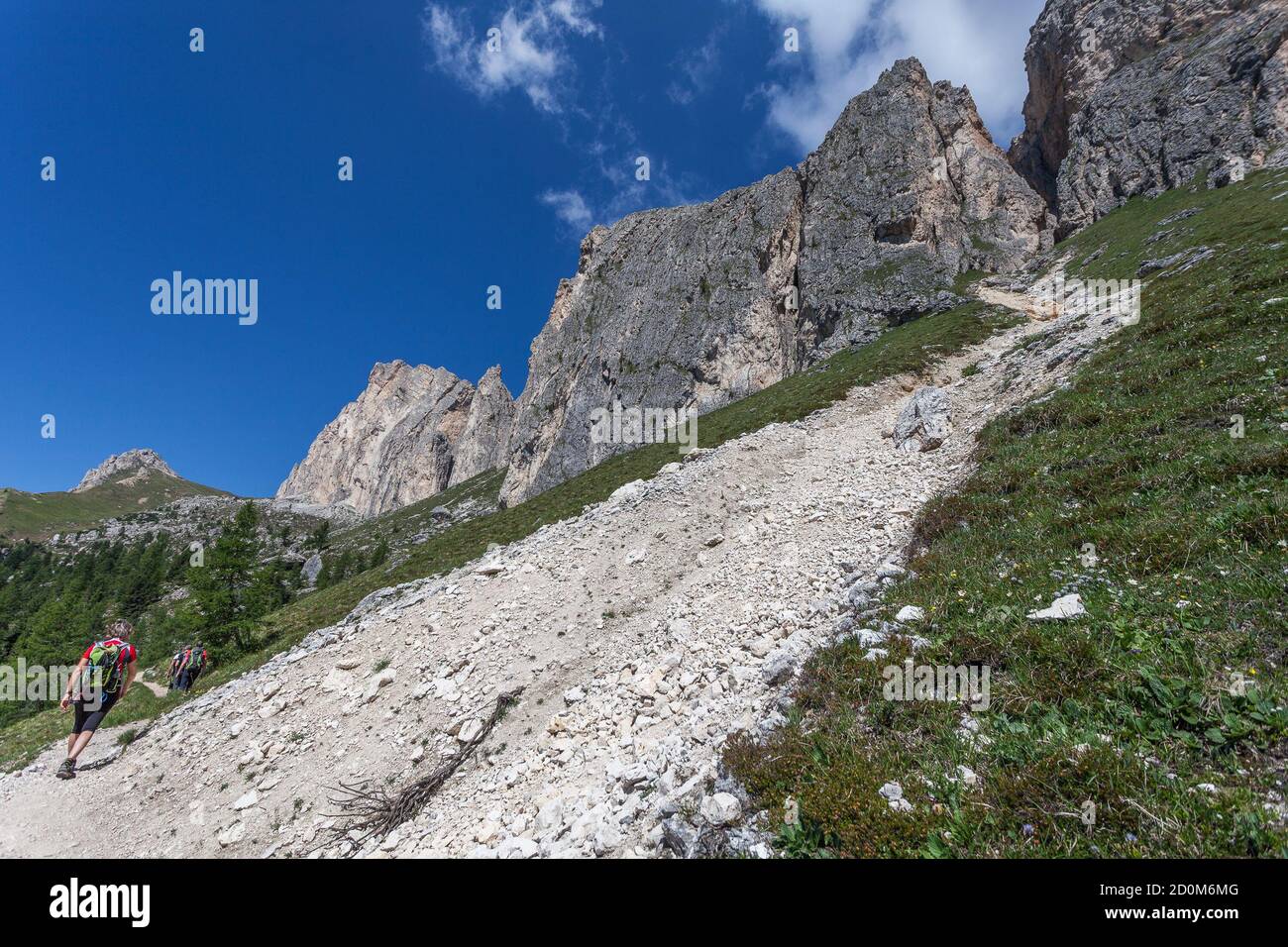 Persone irriconoscibili che camminano ai germogli di imponente parete di dolomite vicino a un flusso di detriti, Settsass, Dolomiti, Italia Foto Stock
