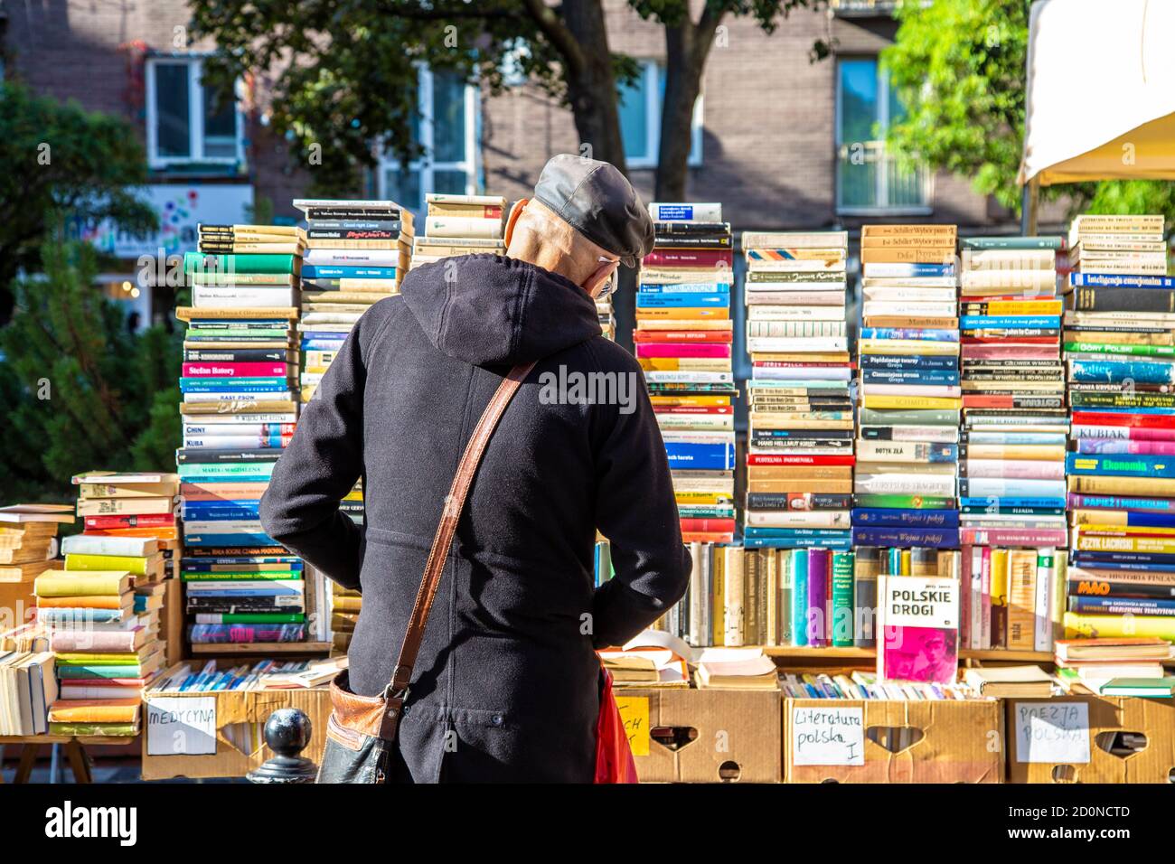 Uomo che guarda i libri di seconda mano allo stallo in via Chmielna a Nowy Swiat, centro di Varsavia, Polonia Foto Stock