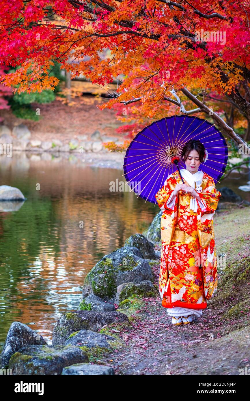 Una bella giovane ragazza giapponese vestita in un kimono colorato nel parco di Nara. Foto Stock