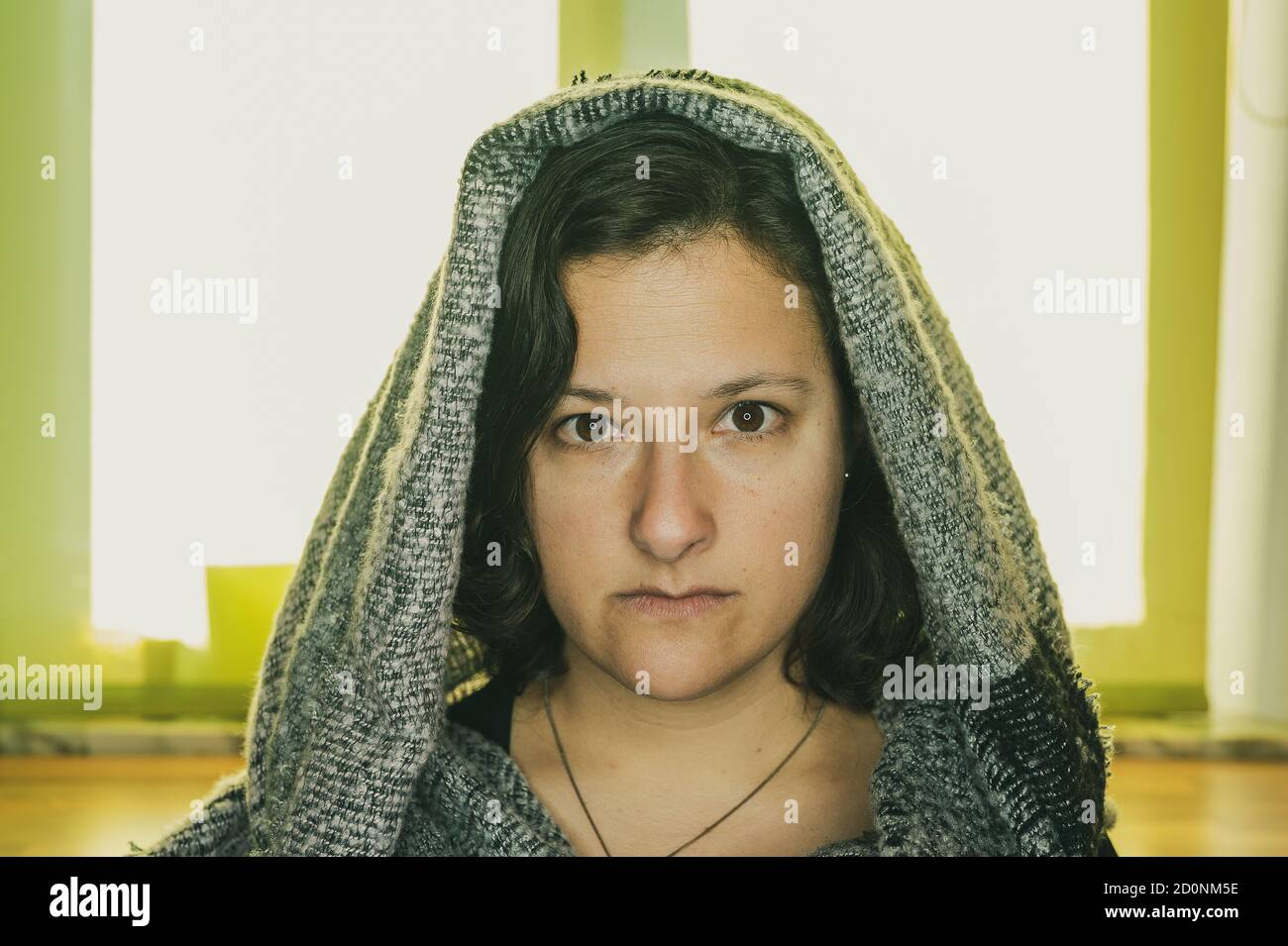 Donna con una cappa di lana guarda seriamente alla macchina fotografica. Foto Stock