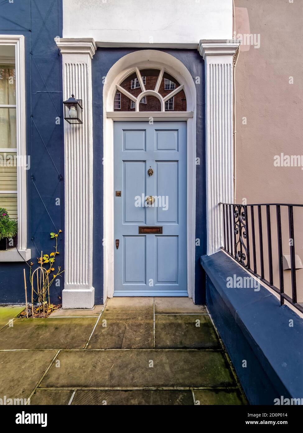 Una porta blu chiaro con una finestra ad arco in architrave a Notting Hill. I semipillari bianchi con frontone piatto sono eccellenti sulle pareti blu scuro e color moka. Foto Stock