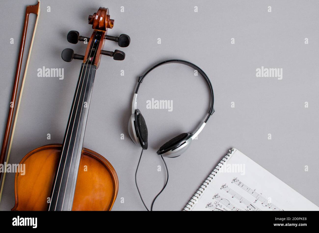 violino, cuffie e partitura su sfondo grigio Foto Stock