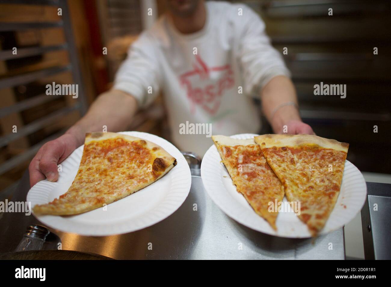Mason Wartman, ex ricercatore di Wall Street, proprietario della pizza  fresca di Rosa, raggiunge il 10 gennaio 2015 per riscaldare le fette di  pizza a Philadelphia, Pennsylvania. La pizzeria da 1 dollaro