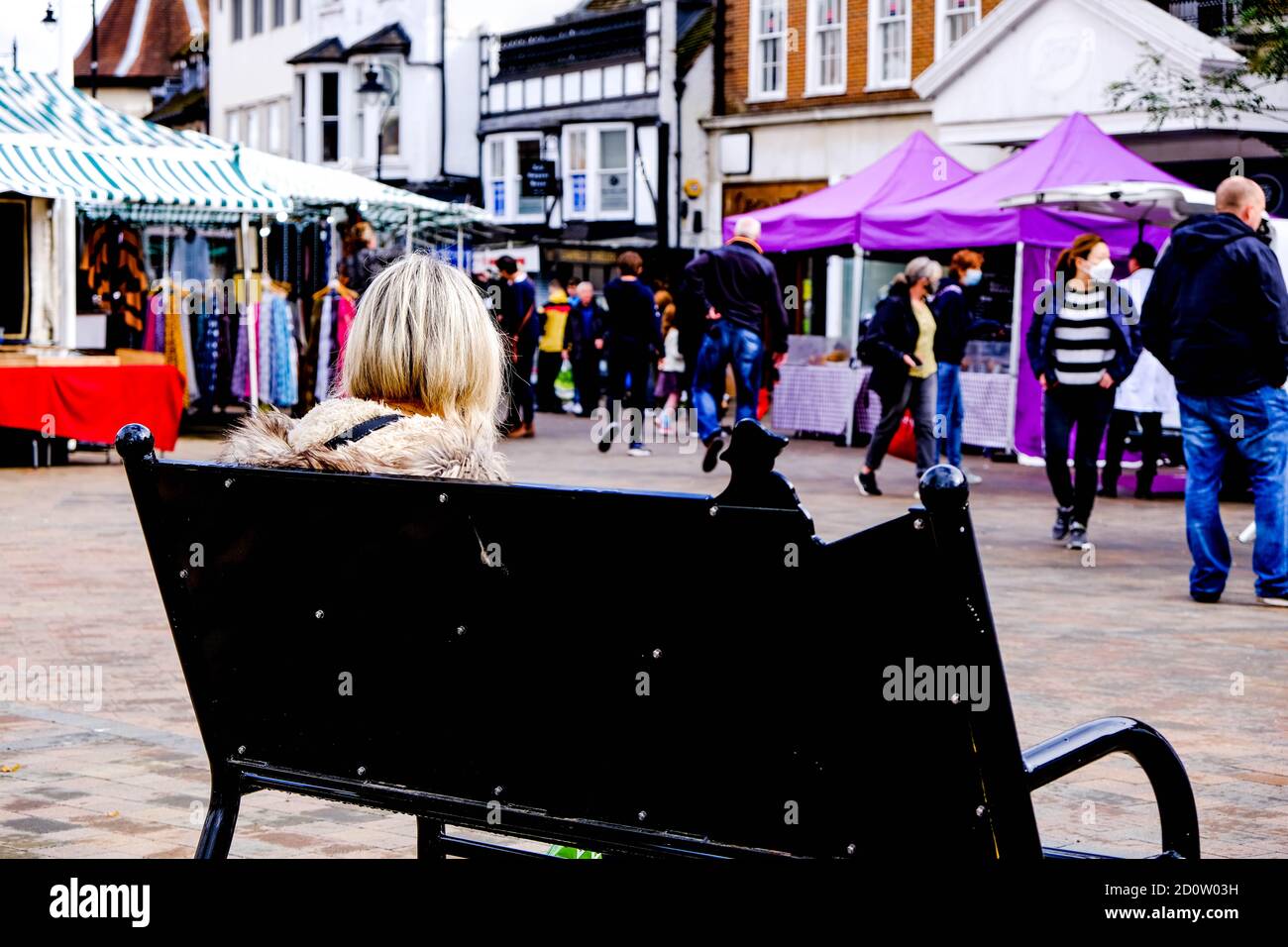 Londra UK, ottobre 03 2020, Donna seduta da sola nel mercato Epsom la gente che guarda durante COVID-19 Foto Stock