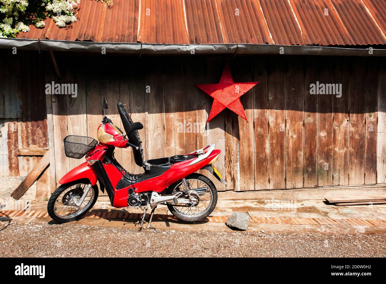 Un parcheggio rosso per motociclette di fronte alla vecchia casa di legno con lanterna rossa di carta. Luang Prabang, Laos, UNESCO, il patrimonio culturale immateriale. Foto Stock