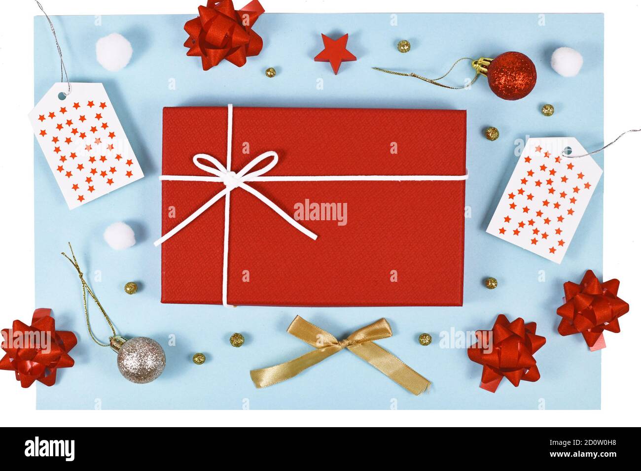 Regalo di Natale con confezione regalo rossa, nastri, etichette regalo, ornamenti di alberi e palle di neve su sfondo azzurro Foto Stock