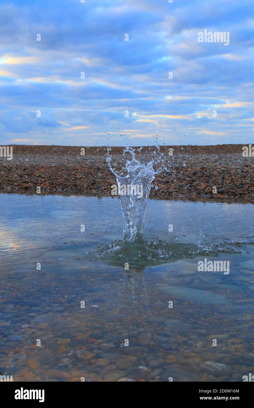 Spruzzi d'acqua sulla spiaggia di ciottoli di Jurassic Coast in Devon Foto Stock