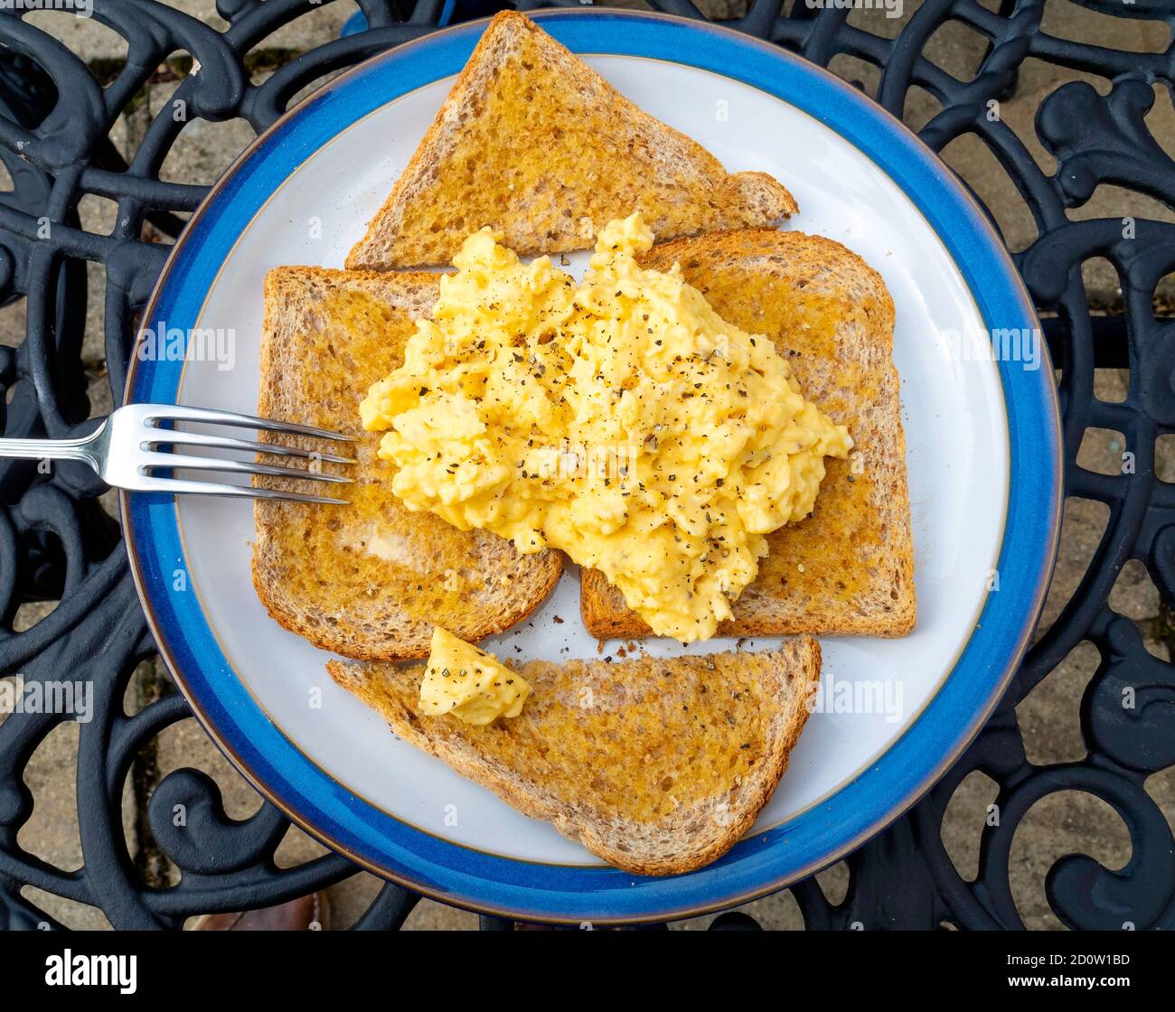 Brunch con colazione o pranzo anticipato su un tavolo all'aperto con sbirciatura uova su pane tostato a grani multipli Foto Stock