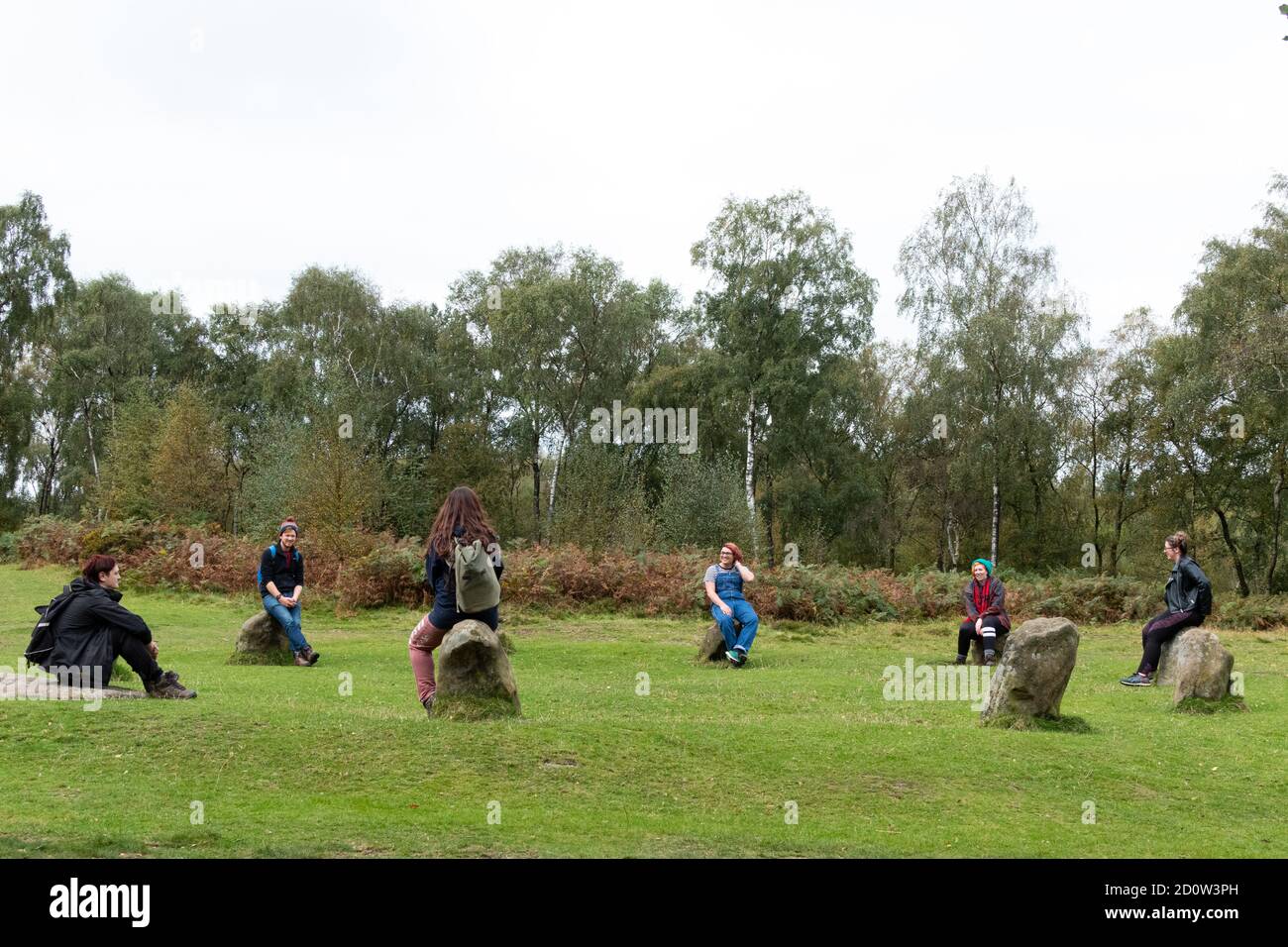 I visitatori si siedono sulle pietre del Nine Ladies Stone Circle nel Peak District National Park, Inghilterra, Regno Unito Foto Stock