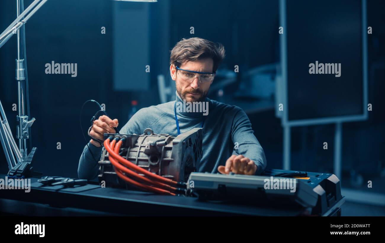 Ingegnere automobilistico professionale in occhiali con computer e ispezione Gli attrezzi sta testando un motore elettrico usato in un alto Laboratorio tecnico con un Foto Stock