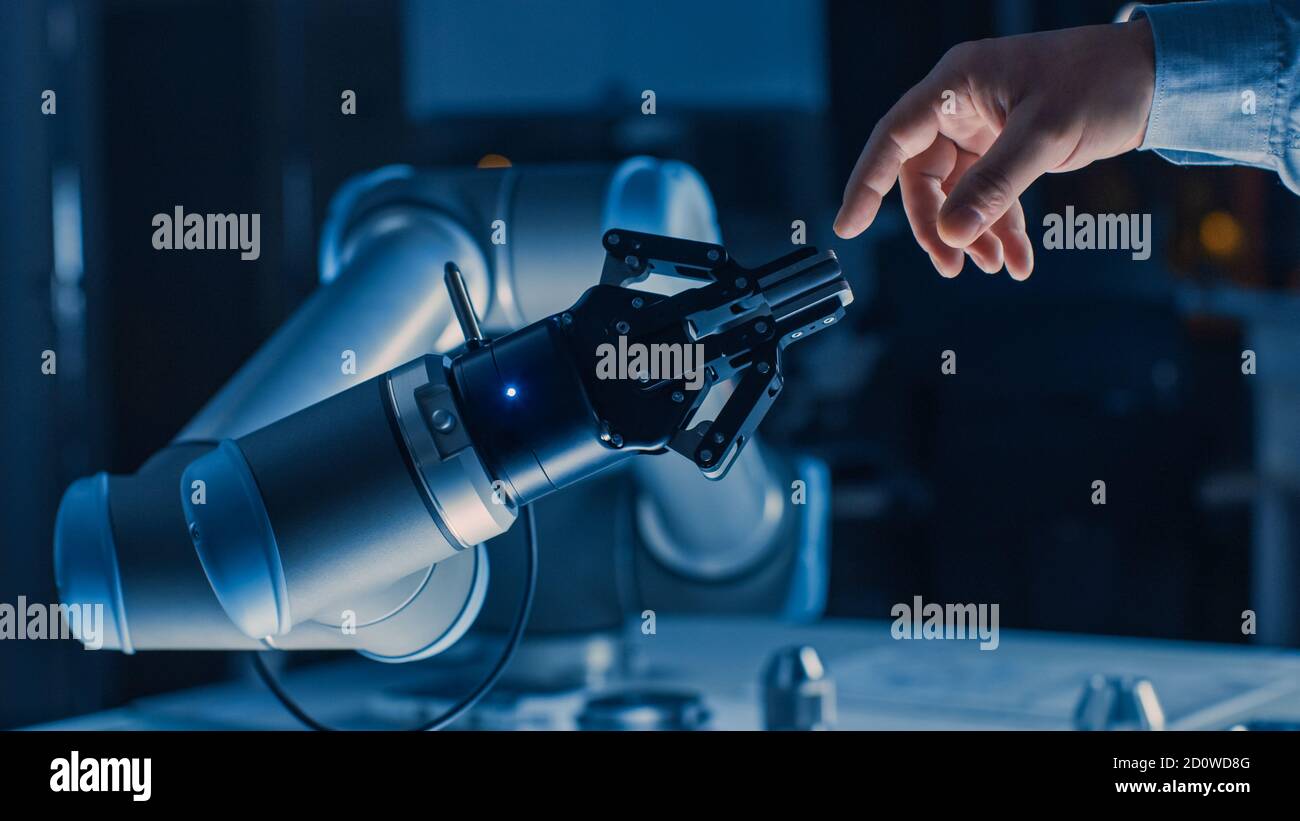 Il braccio robotico futuristico tocca la mano umana nell'umanità e l'intelligenza artificiale unificando il gesto. La tecnologia cosciente incontra l'umanità. Concetto Foto Stock