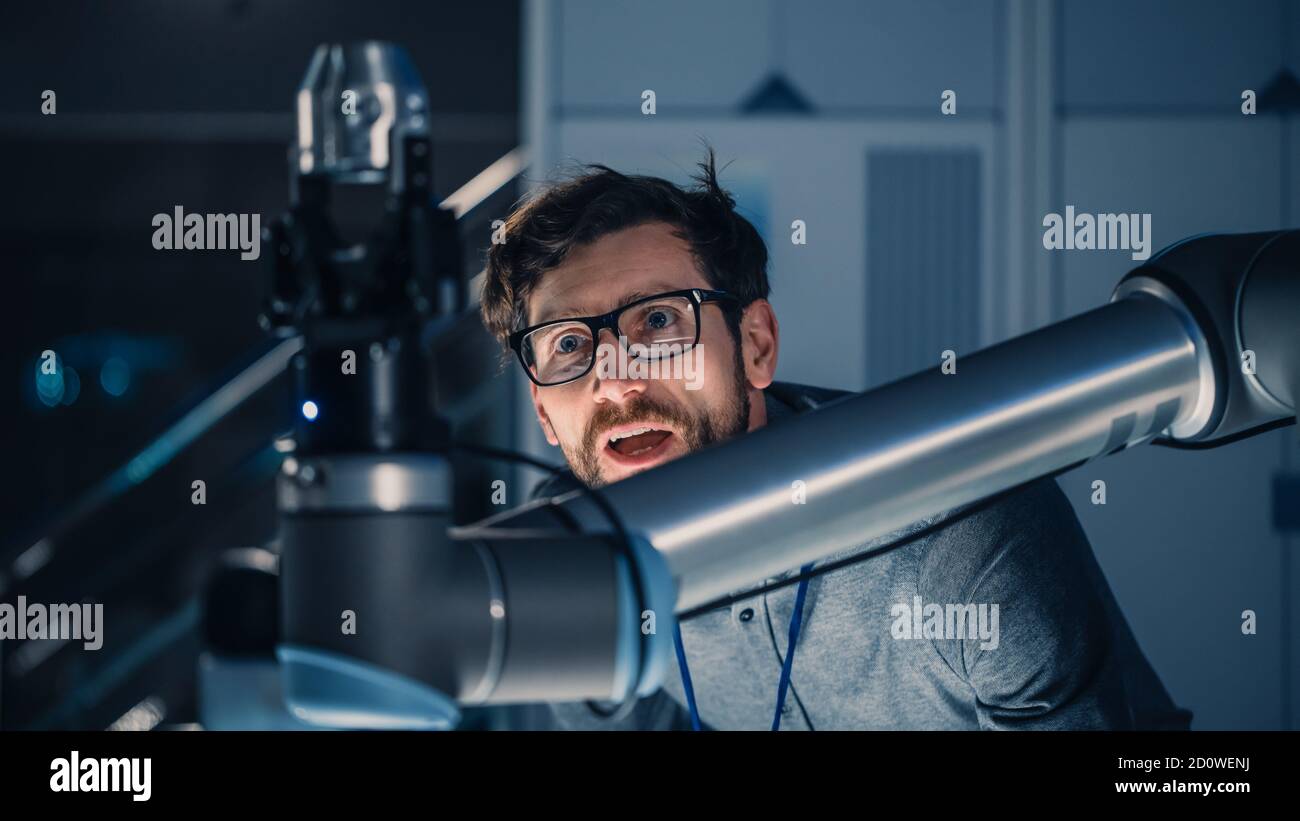 Shot of a Mechanical Engineer lavora con il futuristico braccio robotico. Il robot sta spostando un oggetto metallico. High Tech Research Laboratory con attrezzature moderne. Foto Stock