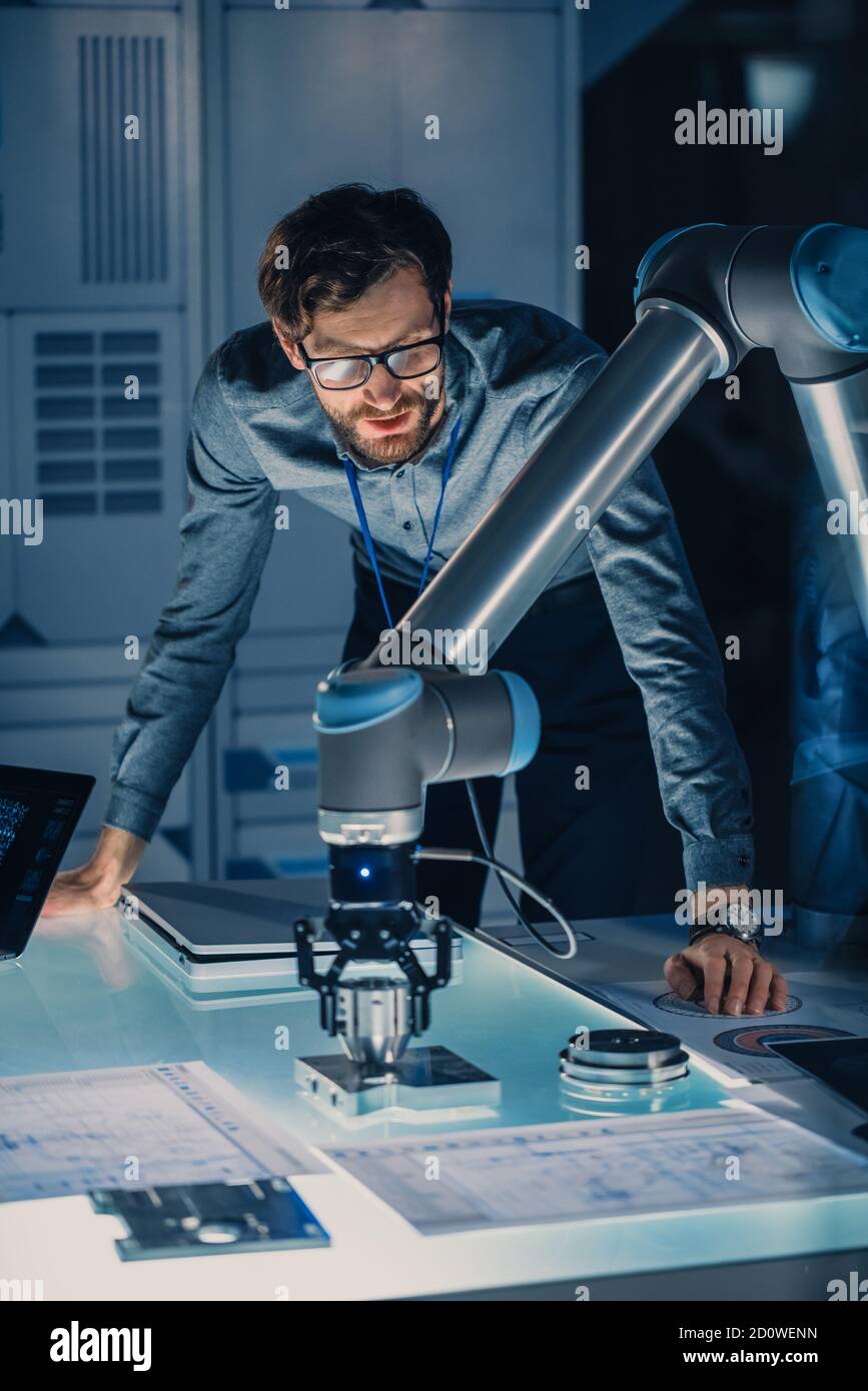 Vertical Shot of a Mechanical Engineer lavora con il futuristico braccio robotico e lo programma per oggetti metallici in movimento. High Tech Research Laboratory con Foto Stock