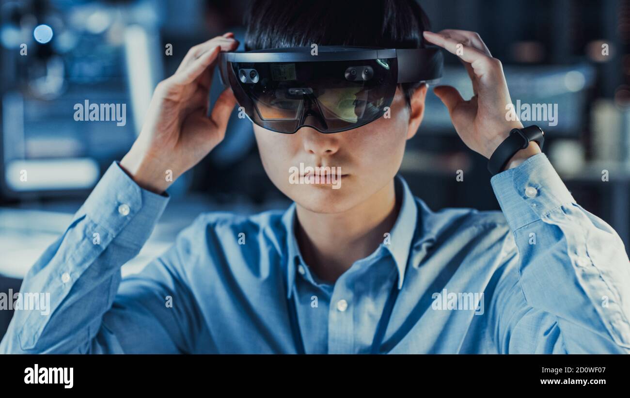 Il professionista giapponese di sviluppo di elettronica Engineer in camicia blu sta indossando Una cuffia per realtà virtuale e un'idea dell'High Tech Ricerca Foto Stock