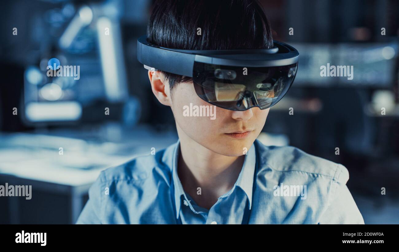 Il professionista giapponese di sviluppo di elettronica Engineer in camicia blu sta indossando Una cuffia per realtà virtuale e un'idea dell'High Tech Ricerca Foto Stock