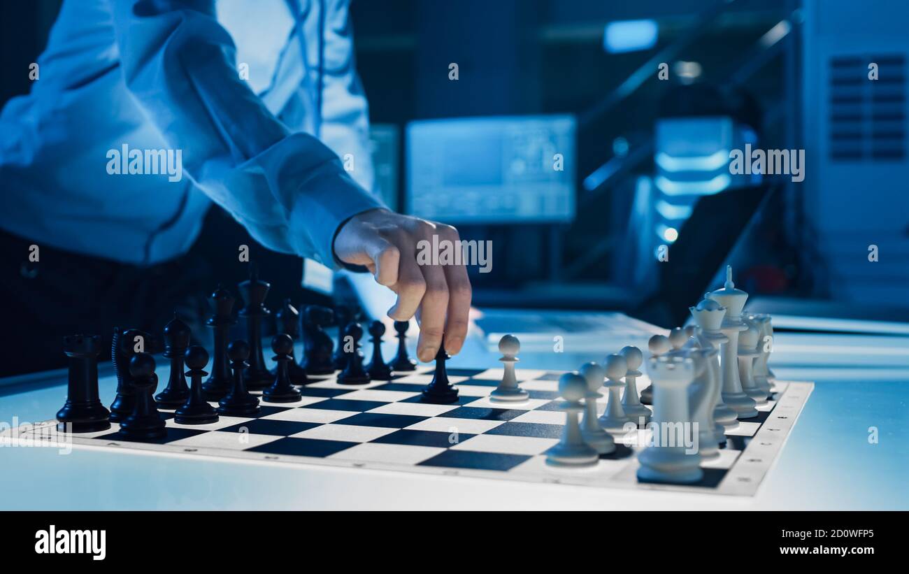 Primo piano colpo di intelligenza artificiale che aziona un braccio robotico futuristico in un gioco di scacchi contro un uomo. Robot sposta un'alba. Sono in un Foto Stock