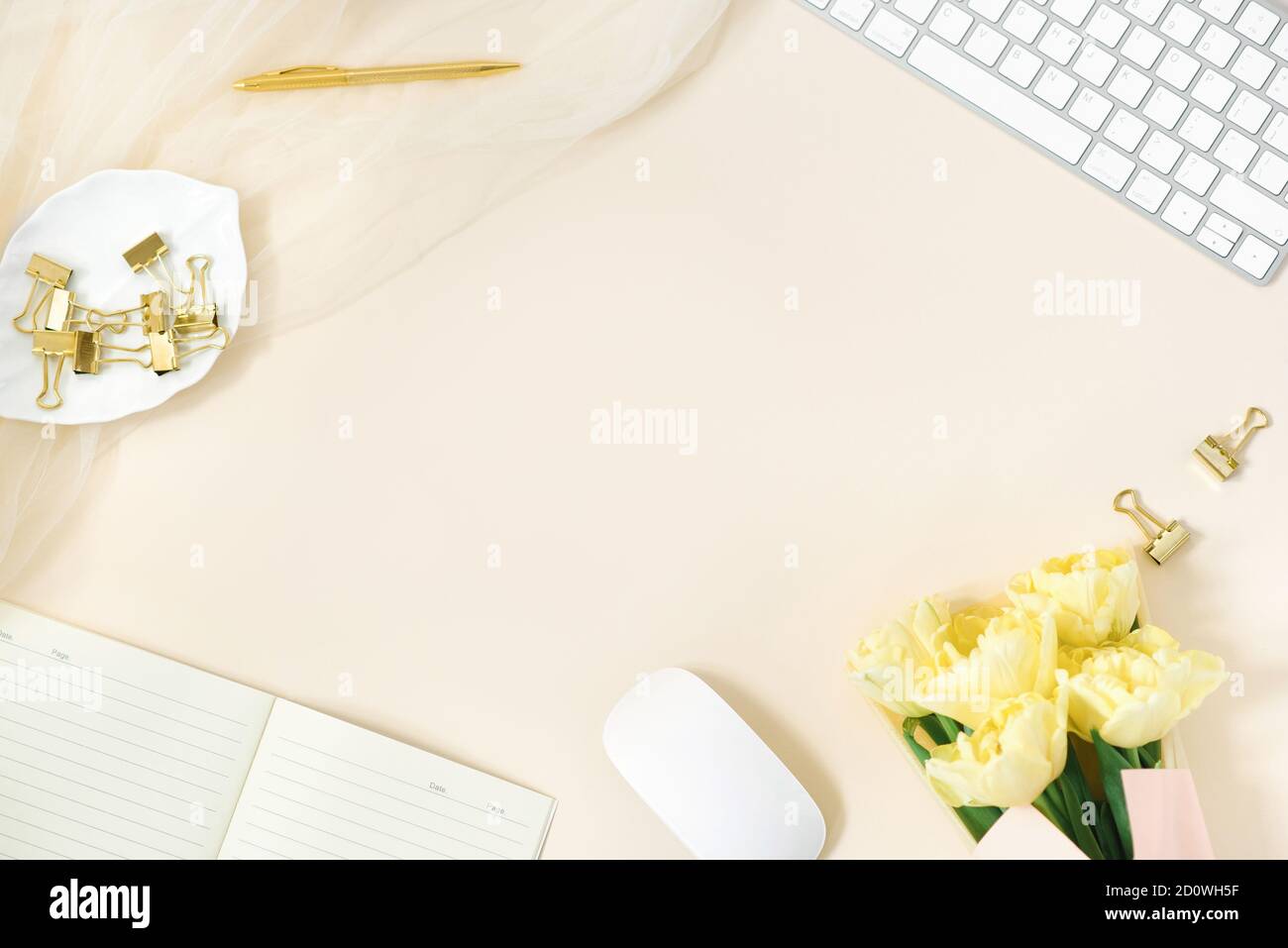 Moderna scrivania home Office, spazio di lavoro con spazio per fotocopie, un bouquet di tulipani gialli su sfondo beige. Lay Flat, il layout della vista superiore. Sfondo per a. Foto Stock