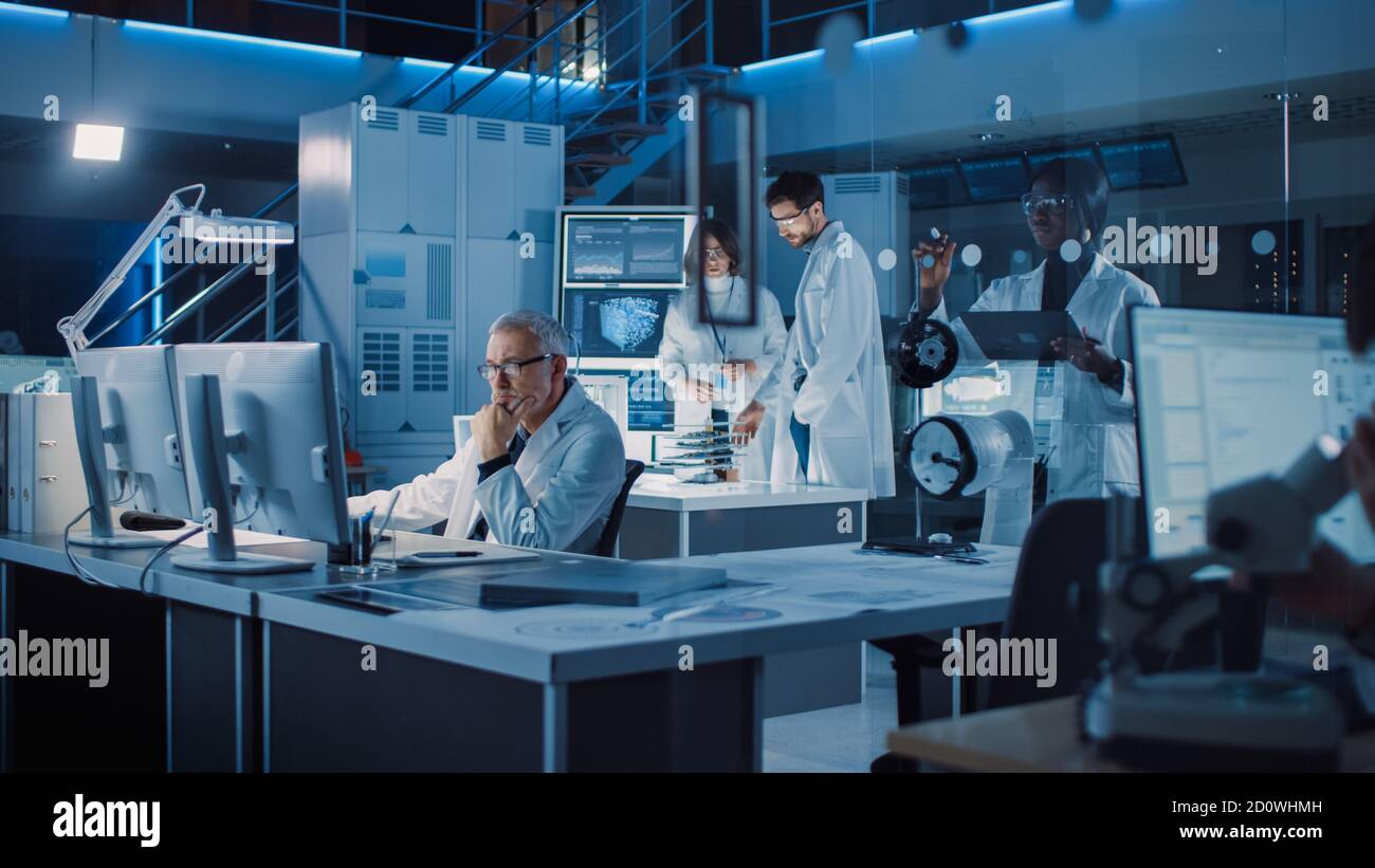 Team internazionale di scienziati e ingegneri industriali che indossano il bianco Cappotti che lavorano alla progettazione di macchinari industriali in laboratorio di Ricerca Foto Stock