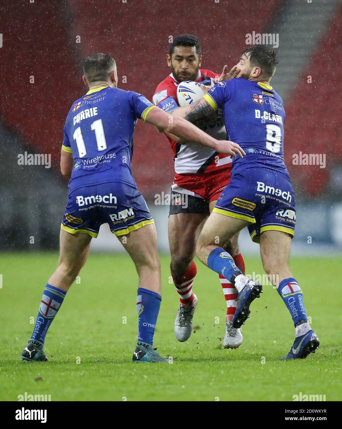 Salford Red Devils' Sebastine Ikahihifo (centro) affrontato da Warrington Wolves' Daryl Clark durante la Coral Challenge Cup, semifinale al Totally Wicked Stadium, St Helens. Foto Stock