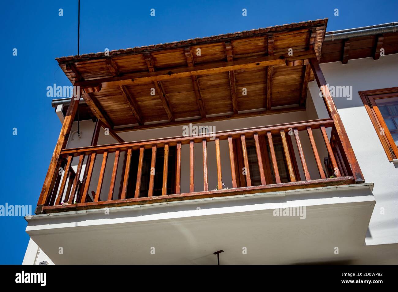 Spring Street vista ad angolo basso, balcone e cielo dalla città di Metsovo, Epiro, Grecia. La struttura è popolare stazione sciistica invernale greca con vecchie case in stile balcanico Foto Stock