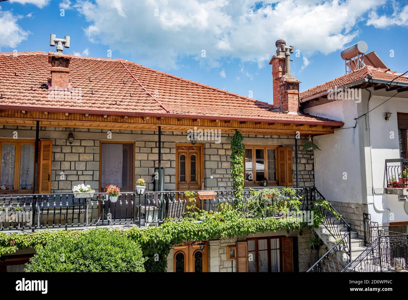 Spring Street vista ad angolo basso, balcone con colorati fiori in vaso e cielo dalla città di Metsovo, Epiro, Grecia. La struttura è popolare stazione sciistica invernale greca con vecchie case in stile balcanico Foto Stock