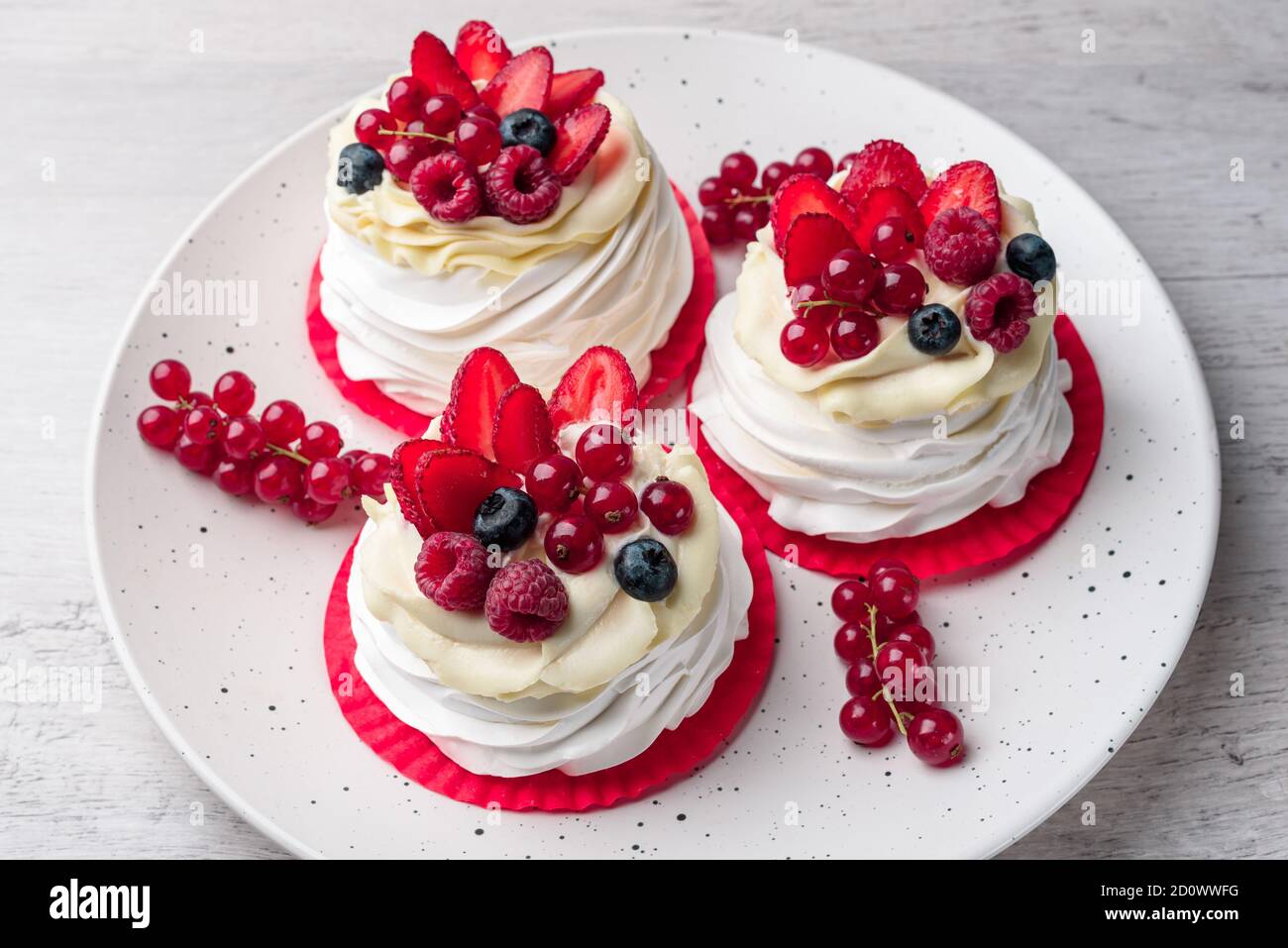 Torta di meringa Pavlova con panna e lamponi, mirtilli, fragole, ribes Foto Stock