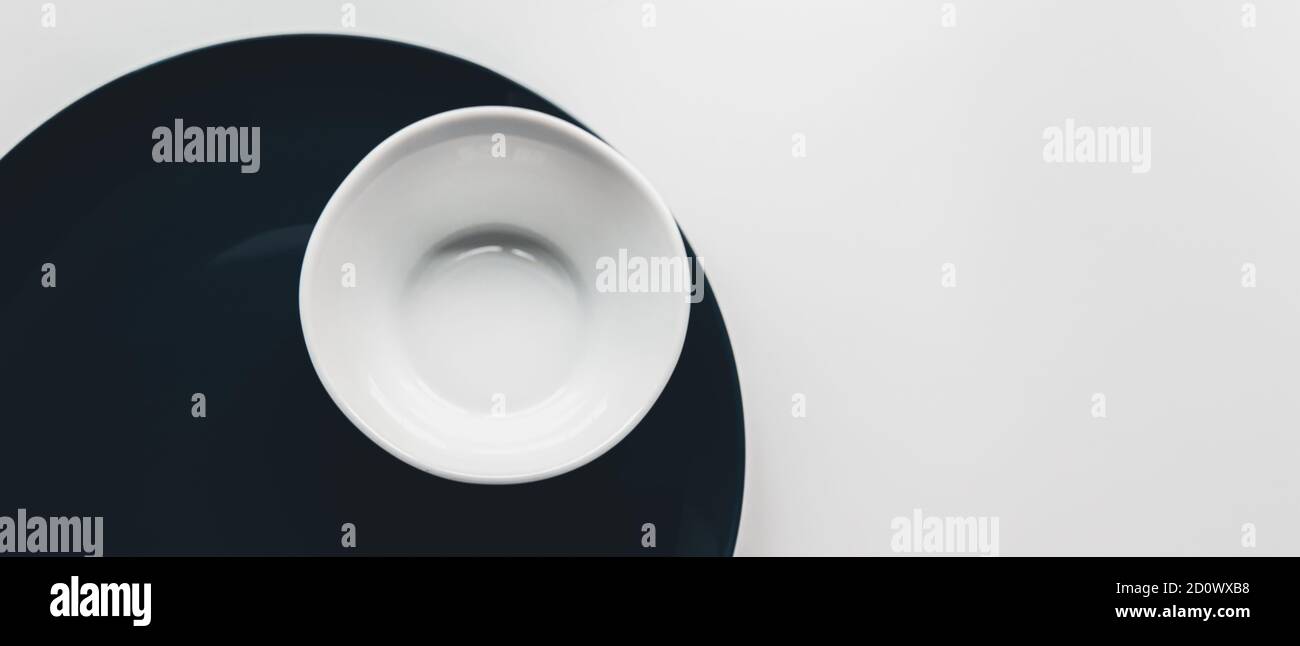 minimalismo. set di grande piatto blu scuro e piccola ciotola bianca su sfondo bianco. concetto di ristorante Foto Stock