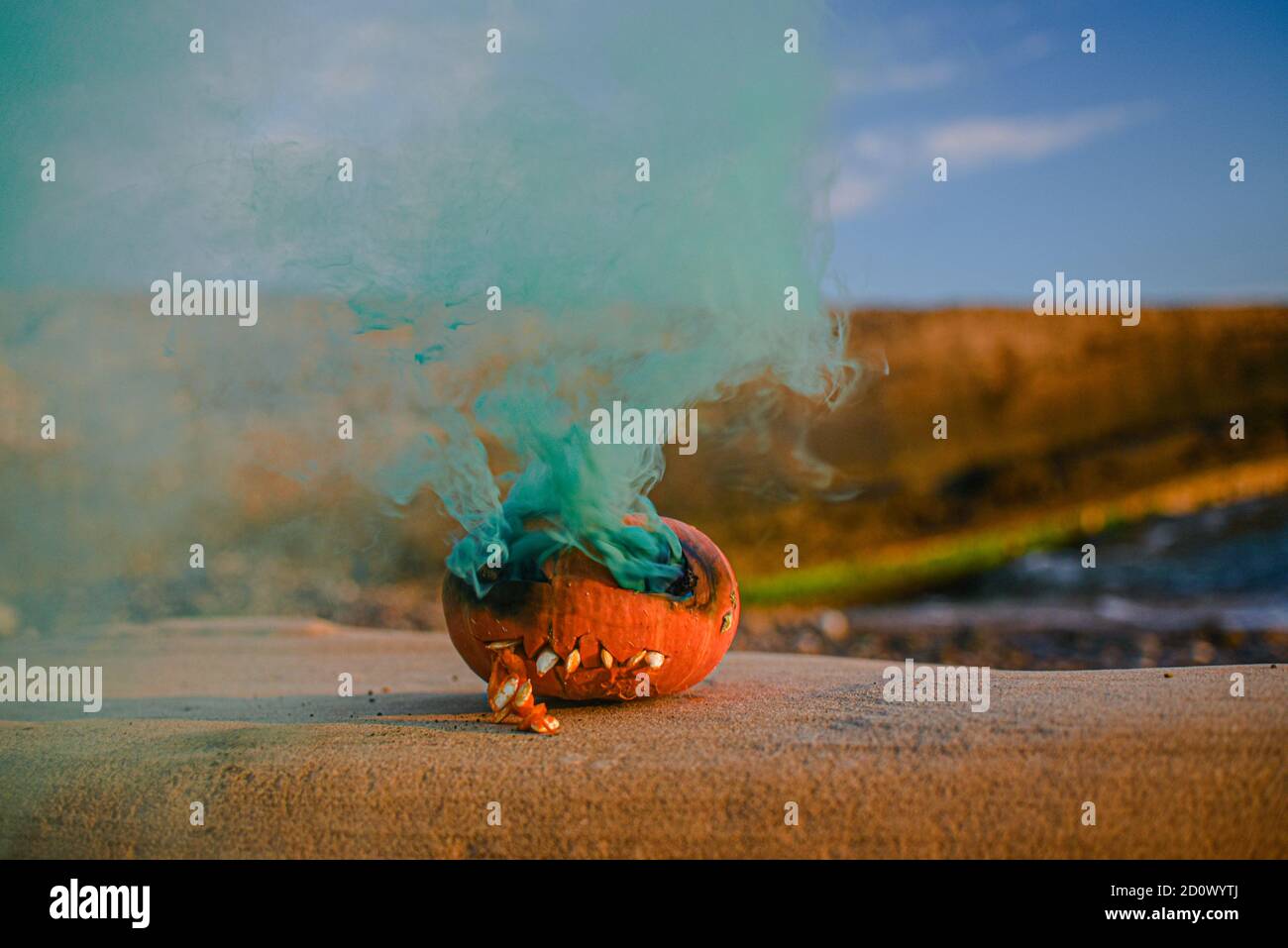 Jack testa di zucca arancione su Halloween si erge su una roccia vicino al mare. Da teste di fumo verde. Terribile bruciato Foto Stock