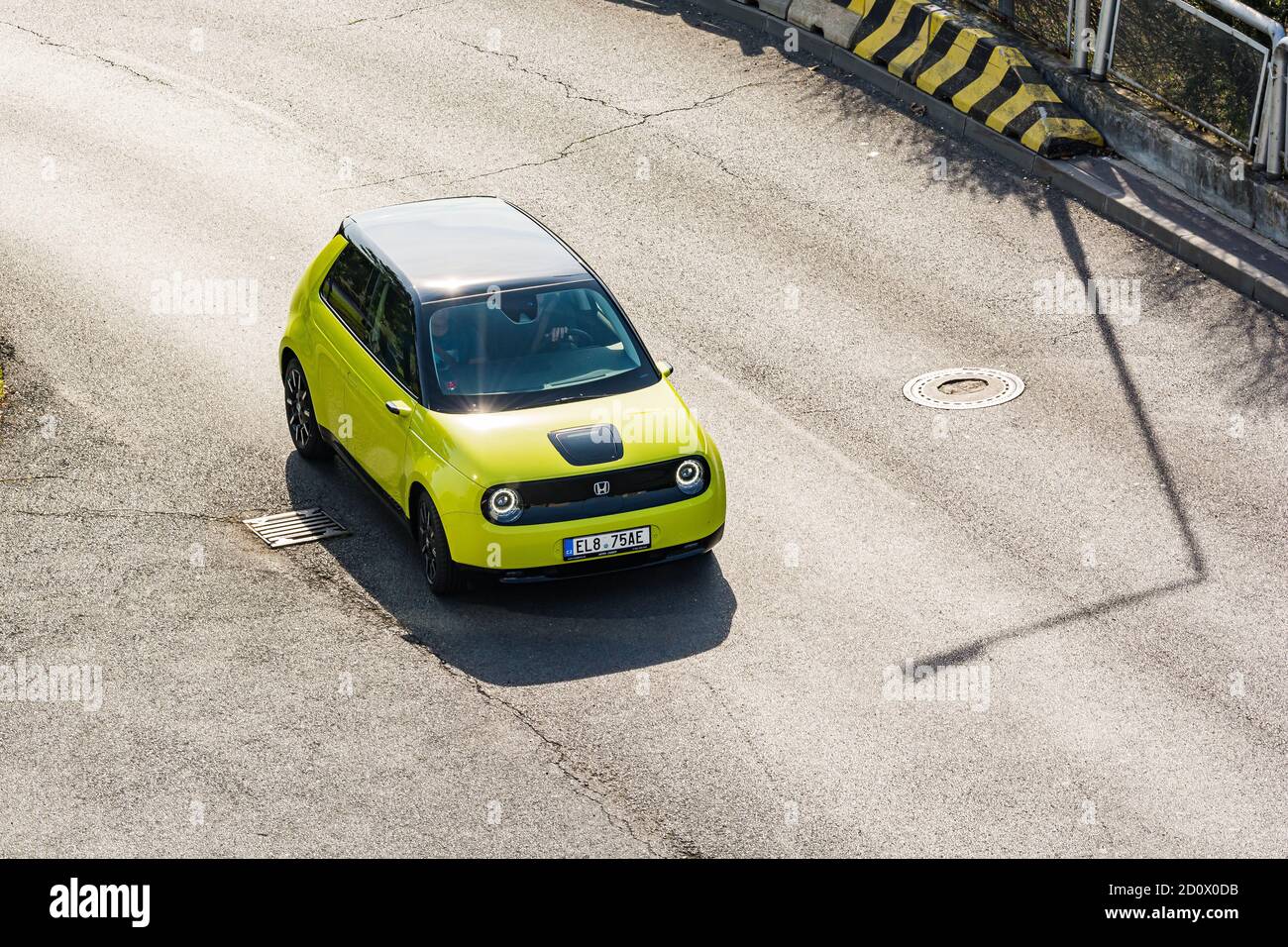 Praga, repubblica Ceca - 02 Ottobre 2020. Giallo verde elettrico Honda e - guida sulla strada catrame - vista sul tetto nero di uccelli prospettiva Foto Stock