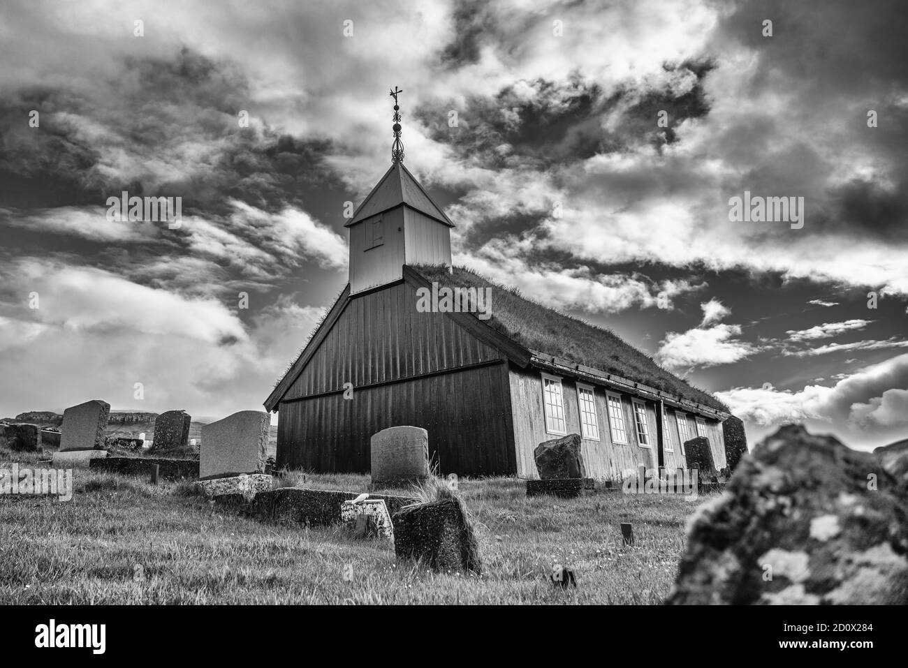 Chiesa di Kaldbak (Kaldbak Kirkja) e cimitero nell'isola di Streymoy in drammatico B & W, Isole Faroe Foto Stock