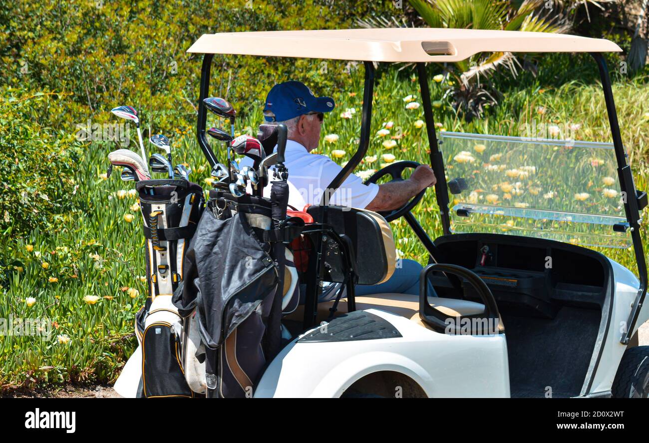 Uomini anziani felici che giocano a golf guidando il golf cart o. buggy sul campo Foto Stock