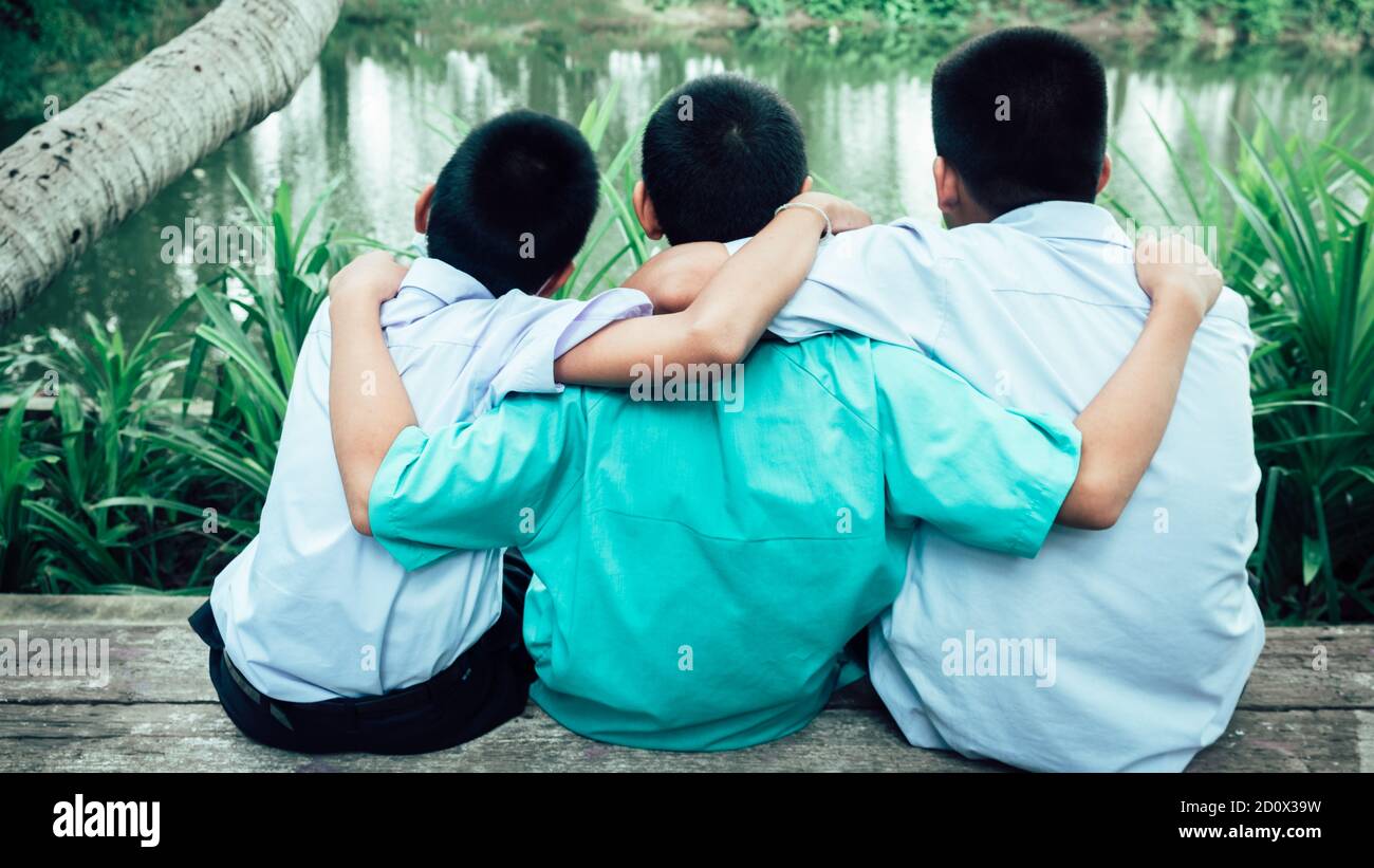 Vista posteriore di tre amici studenti che abbracciano con amore.concetto di migliore amicizia Foto Stock